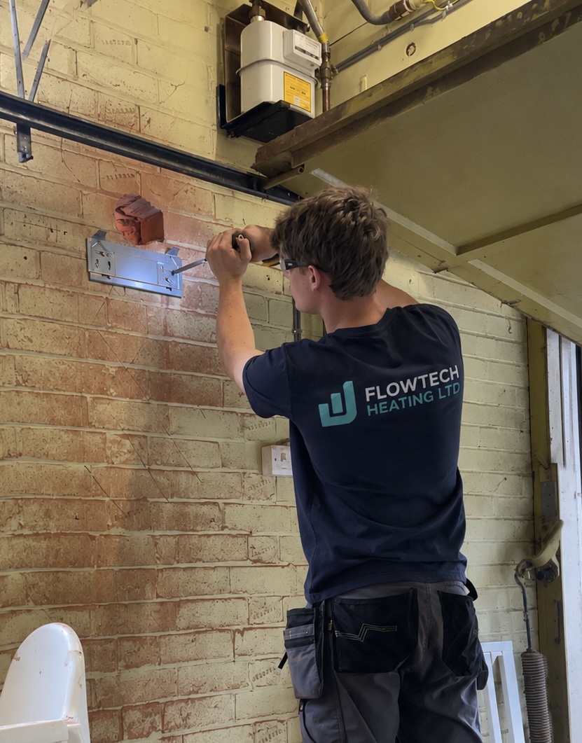 Flowtech Heating engineer working on a wall-mounted boiler
